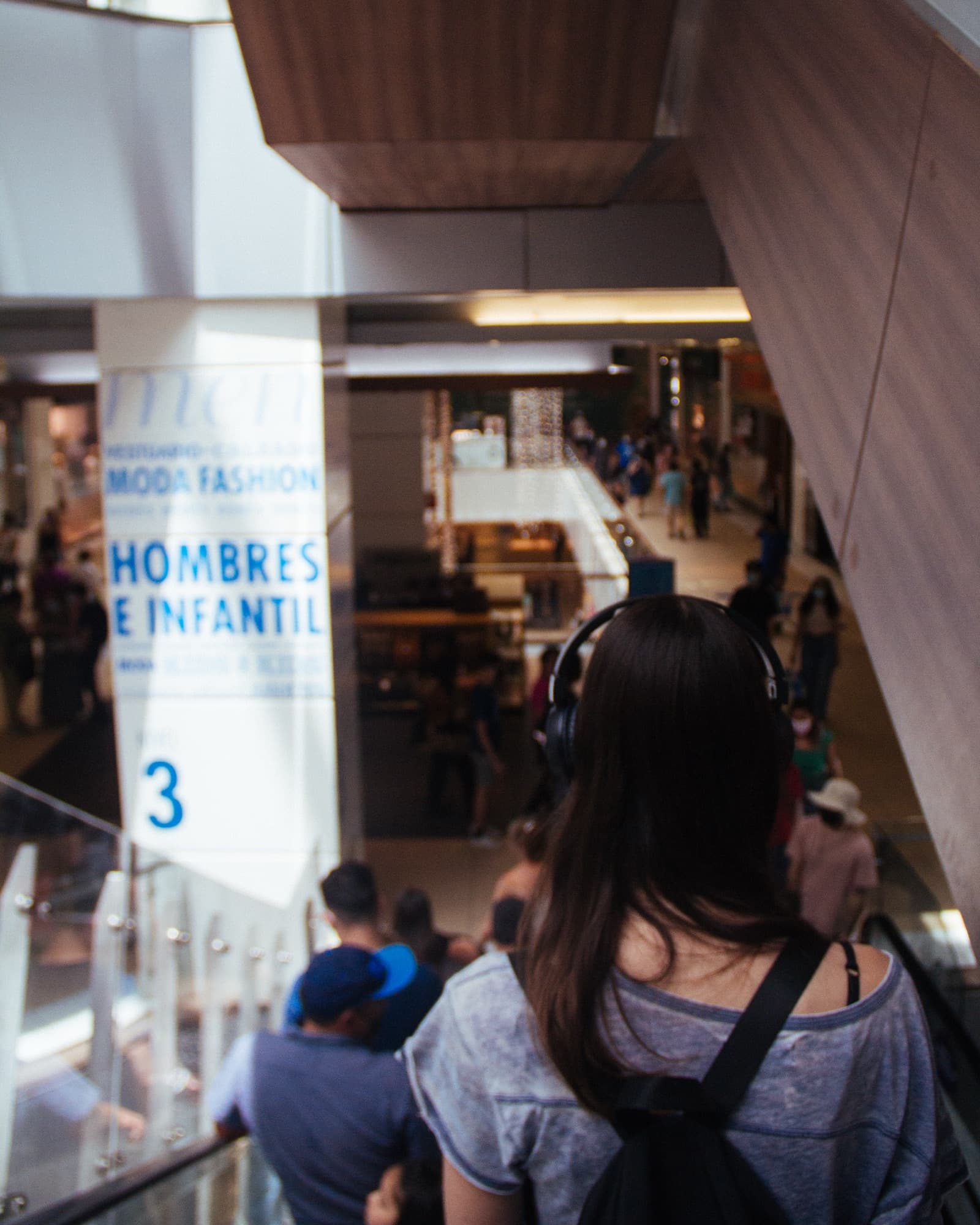 A listener with headphones rides an escalator down through the Costanera Center mall.