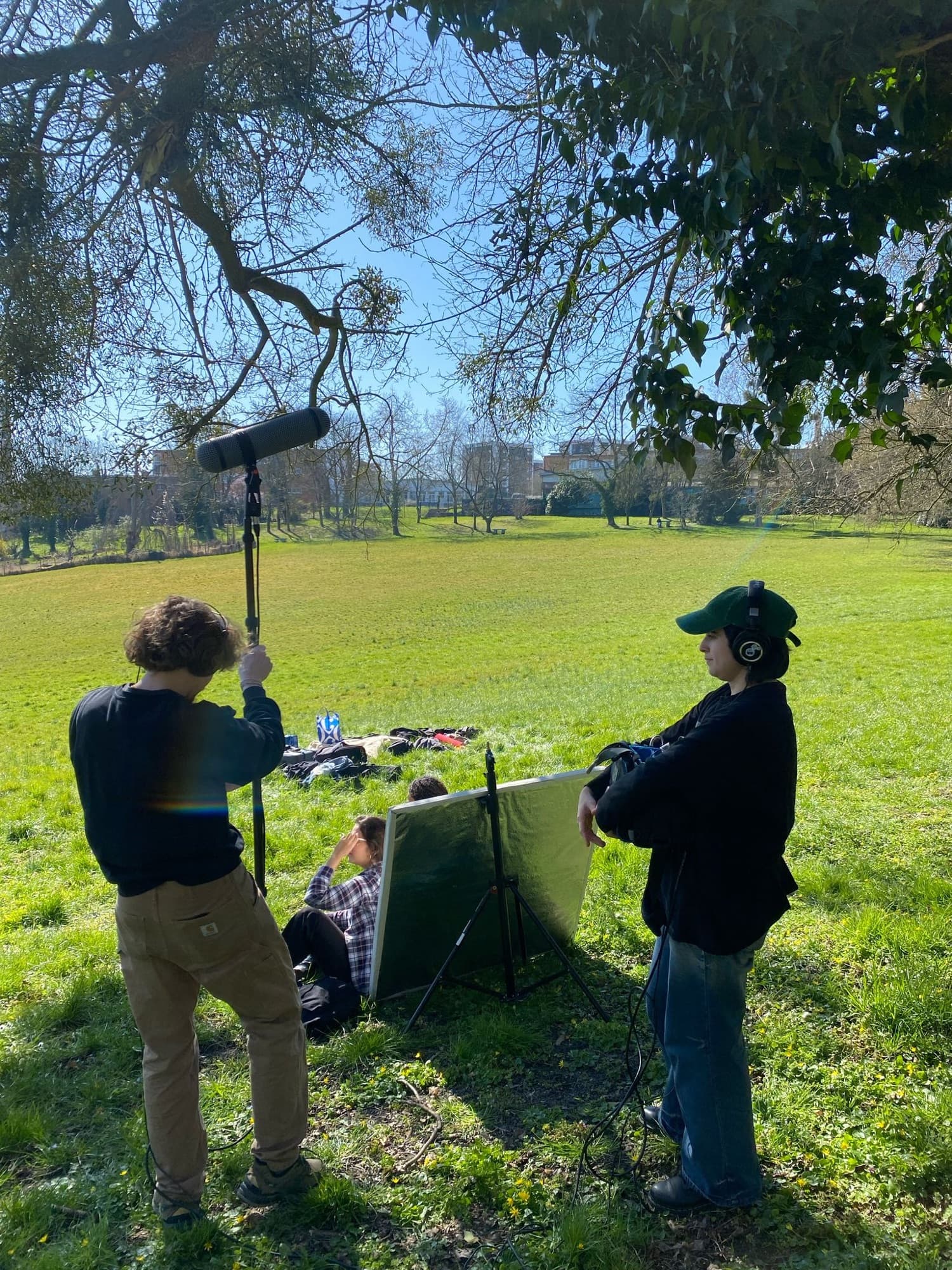 Tournage dans un parc : la perche est tenue au-dessus des interprètes, à côté de Gabriel, casque sur les oreilles.