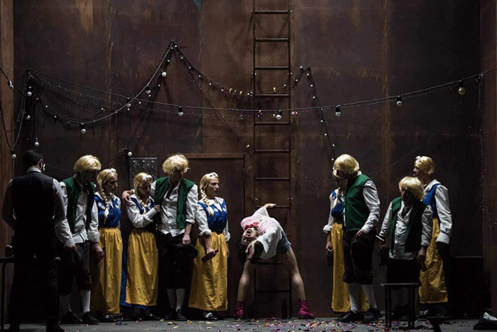 Signorina Giulia: an ensemble in blond wigs and folk costumes surrounds a performer bending backwards.